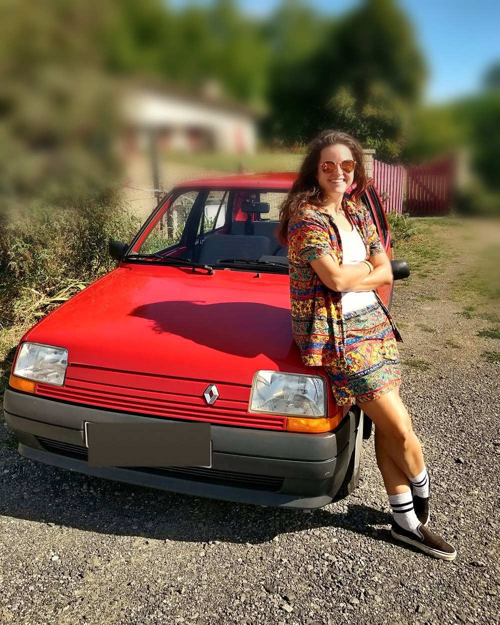 Photo: Audrey in sunglasses, leaning on the red Super 5, in the sun